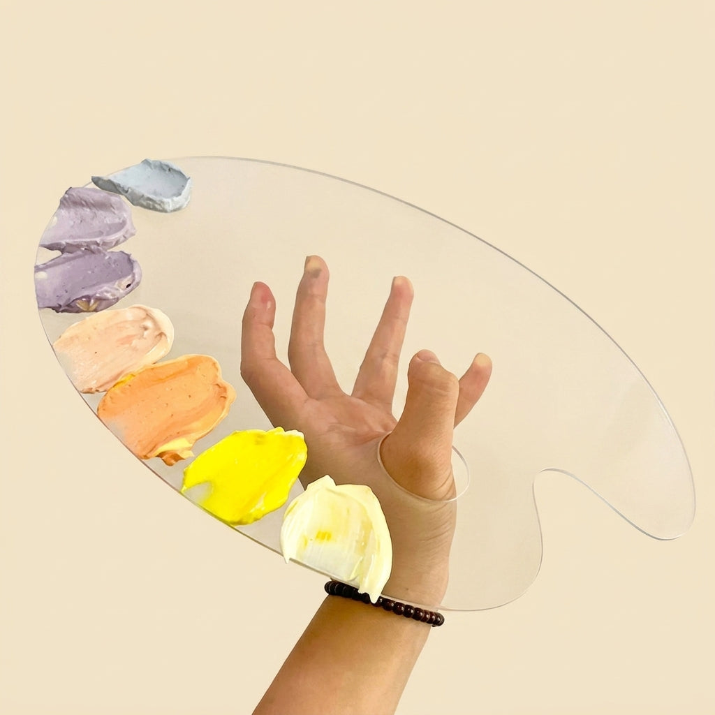 A clear acrylic paint palette held by a hand, with several paint colors visible on the left side, against a solid beige background.