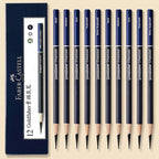 A set of 12 Faber-Castell Goldfaber charcoal pencils arranged next to their dark blue packaging box on a light beige background. The pencils have dark blue barrels with white text indicating different graphite grades (H, M, B, F, 2H, 2B, 3B, 4B, 5B, 6B, 7B, 8B, 9B, 10B, 12B) and are shown with their sharpened tips.
