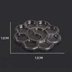A clear plastic flower-shaped tray with multiple circular compartments, shown on a dark background with white dimension lines indicating 12CM by 12CM measurements.